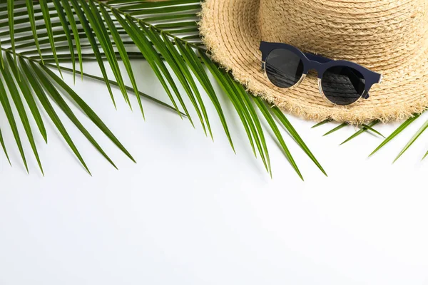 Beyaz üzerinde hasır şapka, güneş gözlüğü ve palmiye yaprakları ile kompozisyon — Stok fotoğraf