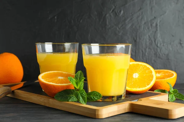 Planche à découper avec jus d'orange, menthe, couteau et oranges sur bois — Photo