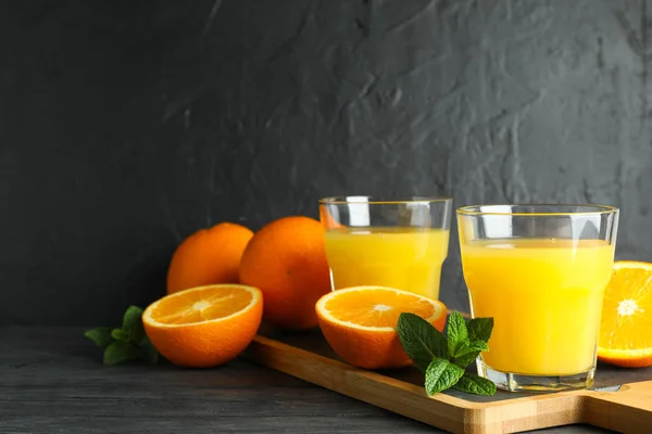 Planche à découper avec jus d'orange, menthe et oranges sur table en bois — Photo