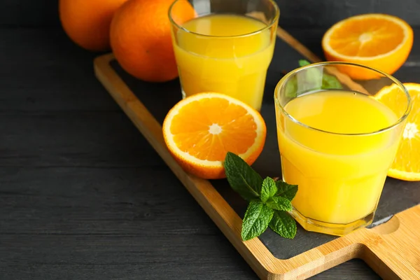 Обробна дошка з апельсиновим соком, м'ятою та апельсинами на дерев'яній тарілці — стокове фото