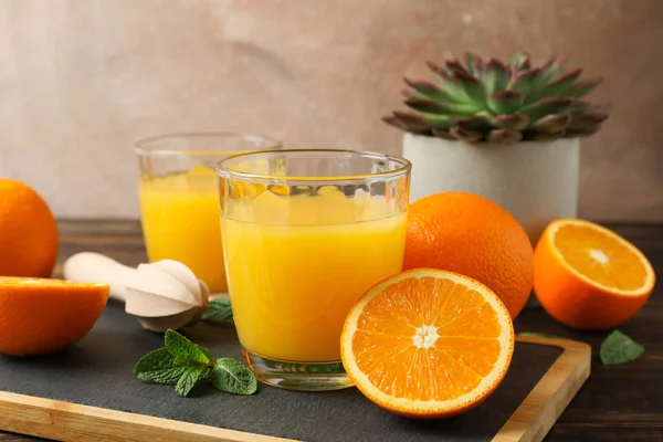 Planche à découper, jus d'orange, presse-agrumes en bois, menthe, orange, tubule — Photo