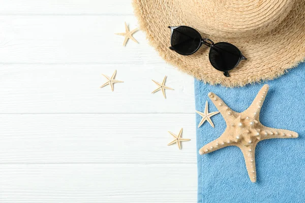 Chapéu de palha, óculos de sol, toalha e estrelas-do-mar em costas brancas de madeira — Fotografia de Stock