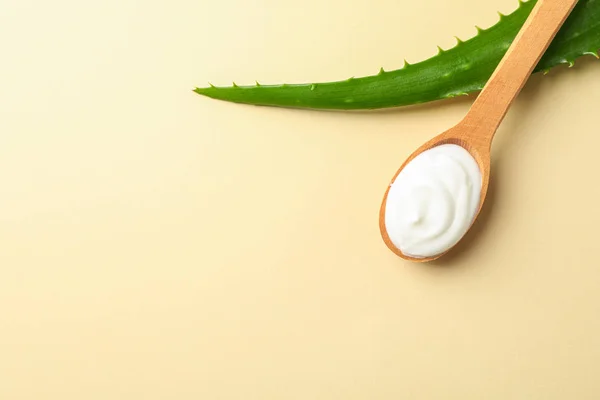 Hoja de aloe vera y cuchara con crema sobre tabla de color, espacio para te — Foto de Stock