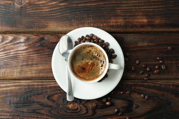 Cup of coffee with spoon and coffee beans on wooden background,