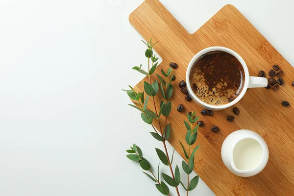 Cutting board with cup of fresh coffee, milk, coffee beans and p — Stock Photo, Image