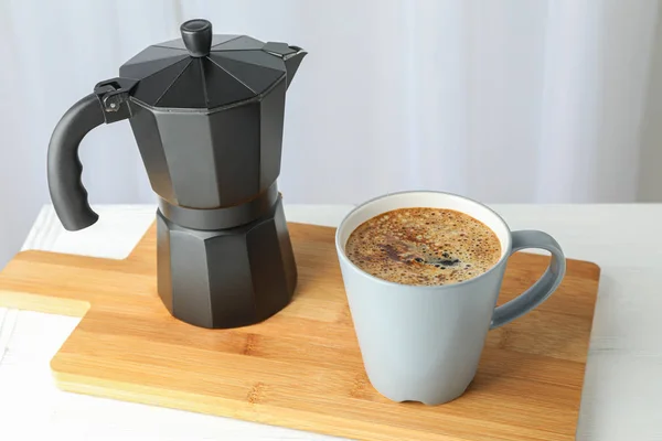 Tabla de cortar con taza de café fresco y cafetera en blanco — Foto de Stock