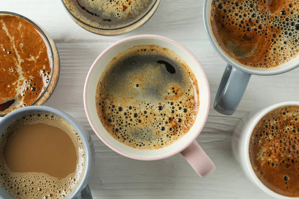 Чашки кофе на белом деревянном фоне, крупный план и вид сверху — стоковое фото