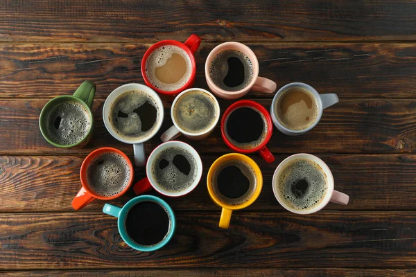 Mehrfarbige Tassen Kaffee auf Holzgrund, Draufsicht und s — Stockfoto