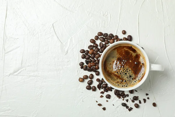 Kopp kaffe med skummande skum och kaffebönor på vit backgro — Stockfoto