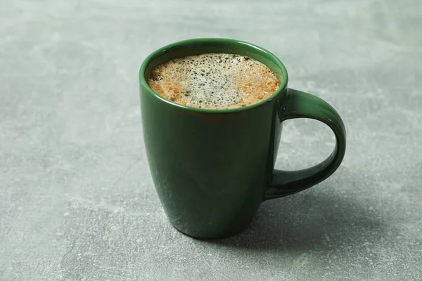 Taza de café con espuma espumosa y granos de café sobre fondo gris — Foto de Stock