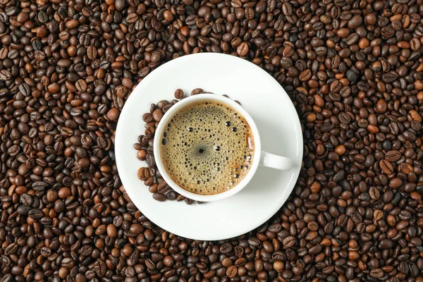 Taza de café con espuma espumosa sobre el fondo de frijoles, vista superior y — Foto de Stock