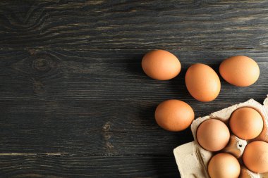 Ahşap masada karton kutuda kahverengi tavuk yumurtası, metin için alan