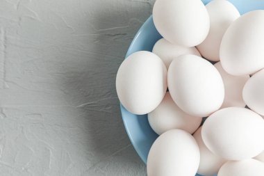Gri masa üzerinde plaka beyaz tavuk yumurtası, metin için boşluk ve