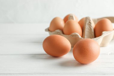 Beyaz arka planda karton kutuda kahverengi tavuk yumurtası, boşluk 