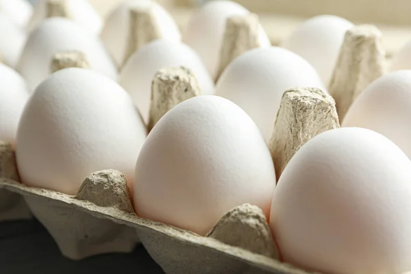 Білі курячі яйця в картонній коробці на дерев'яному столі, крупним планом — стокове фото