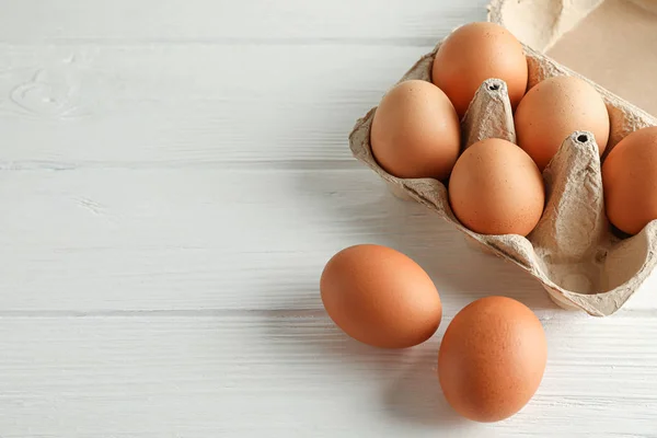 Huevos de pollo marrón en caja de cartón sobre fondo blanco, espacio para — Foto de Stock