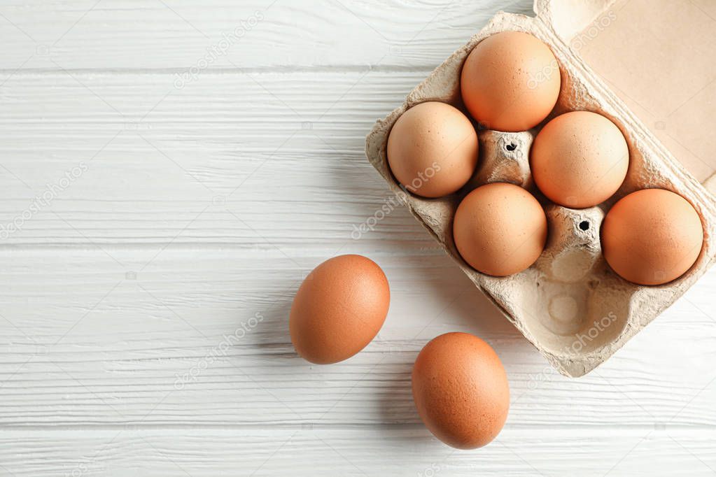 Brown chicken eggs in carton box on white background, space for 