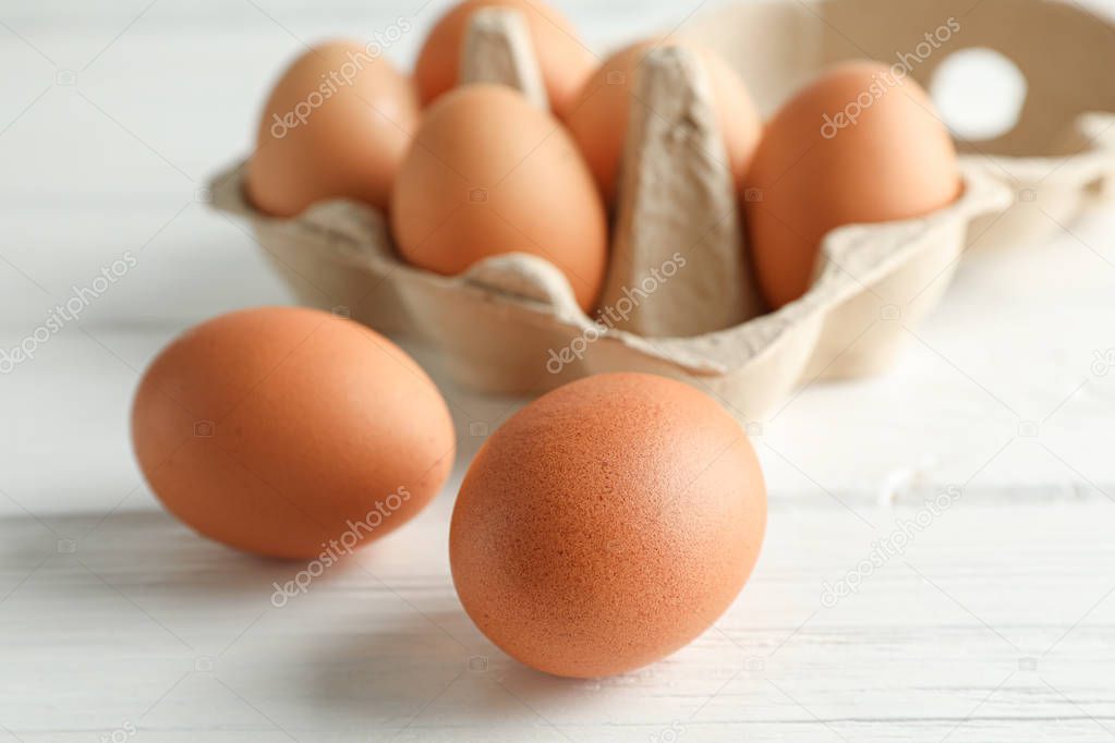 Brown chicken eggs in carton box on white background, space for 