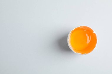Gri arka plan üzerinde sarısı ile yarım kırık yumurta, metin için alan ve
