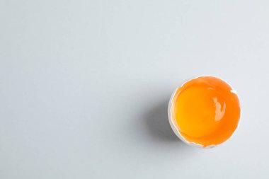 Gri arka plan üzerinde sarısı ile yarım kırık yumurta, metin için alan ve