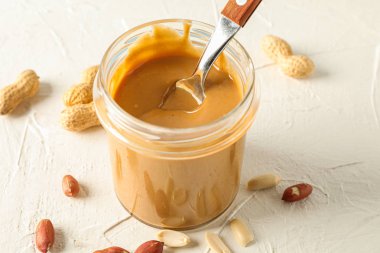 Krem fıstık ezmesi ve kaşık ile cam kavanoz ve WHI üzerinde fıstık