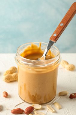 Krem fıstık ezmesi ve kaşık ile cam kavanoz ve WHI üzerinde fıstık