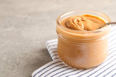 Fıstık ezmesi ve kaşık ile cam kavanoz ve GRE üzerinde mutfak havlusu