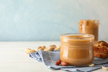 Fıstık ezmesi, fıstık, mutfak havlusu, kaşık ve p ile cam kavanoz