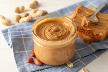 Fıstık ezmesi, fıstık, mutfak havlusu, kaşık ve p ile cam kavanoz