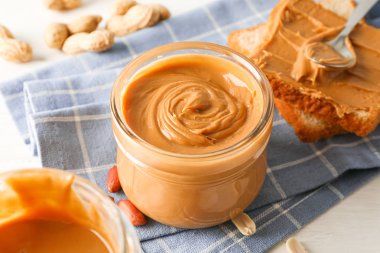 Fıstık ezmesi, fıstık, mutfak havlusu, kaşık ve p ile cam kavanoz