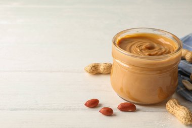 Beyaz üzerinde fıstık ezmesi, fıstık ve mutfak havlusu ile cam kavanoz 