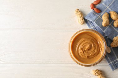 Beyaz üzerinde fıstık ezmesi, fıstık ve mutfak havlusu ile cam kavanoz 