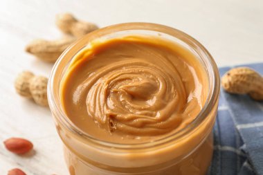 Beyaz üzerinde fıstık ezmesi, fıstık ve mutfak havlusu ile cam kavanoz 