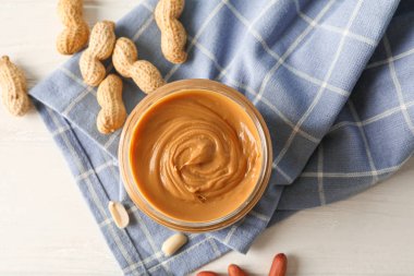 Beyaz üzerinde fıstık ezmesi, fıstık ve mutfak havlusu ile cam kavanoz 