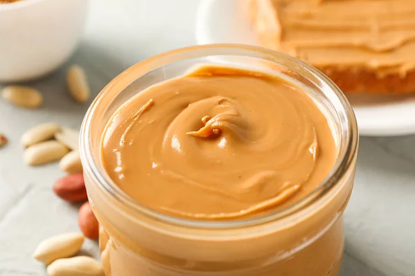 Glass jar with peanut butter, peanut, cup of coffee and peanut b