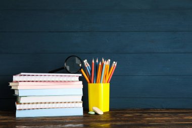 Koyu sırta karşı ahşap masa üzerinde okul malzemeleri ile Kompozisyon