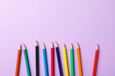 Menekşe backgroun üzerinde çok renkli kalemler ile Düz yatıyordu kompozisyon