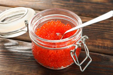 Ahşap masa üzerinde kırmızı havyar ile Cam kavanoz, metin için alan