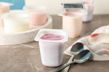 Gri masa üzerinde yoğurt ile plastik bardak ile Kompozisyon, uzay f