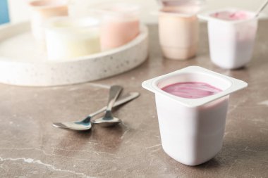 Gri masa üzerinde yoğurt ile plastik bardak ile Kompozisyon, uzay f