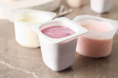 Gri masa üzerinde yoğurt ile plastik bardak ile Kompozisyon, uzay f