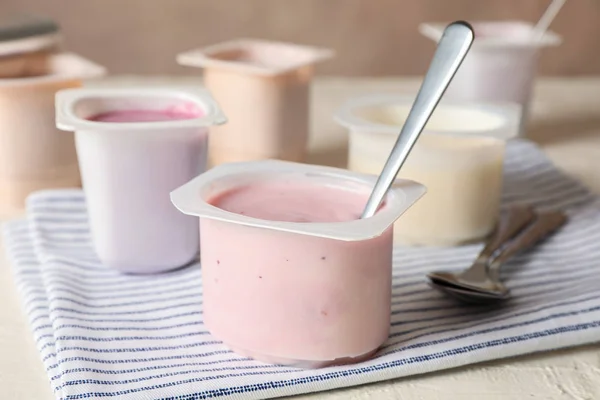 Komposition mit Plastikbechern mit Joghurt auf weißem Tisch — Stockfoto