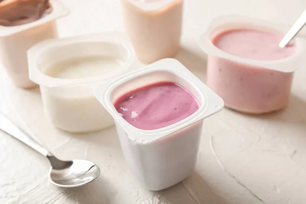Komposition mit Plastikbechern mit Joghurt auf weißem Tisch — Stockfoto