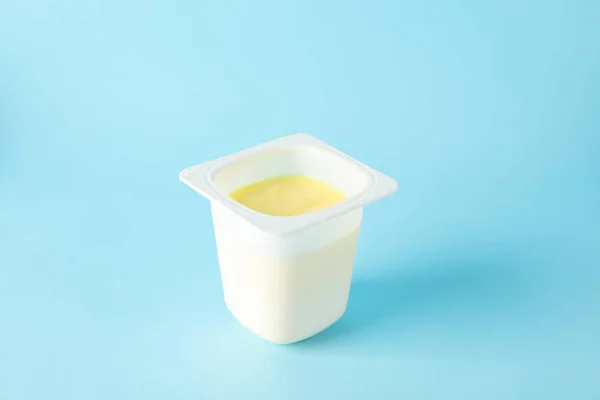 Tazza di plastica con yogurt su sfondo a colori, spazio per il testo — Foto Stock