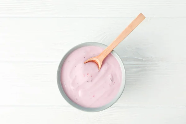 Fruchtjoghurt in Schüssel und Löffel auf weißem Holzhintergrund — Stockfoto