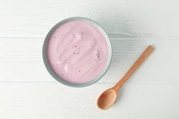 Фруктовый йогурт в миске и ложка на белом деревянном фоне — стоковое фото