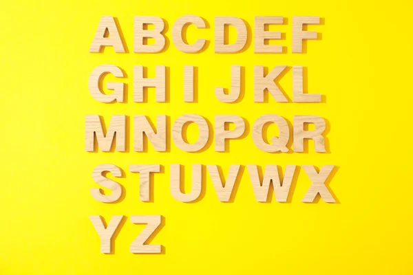 Træbogstaver i engelsk alfabet på farve baggrund, top view - Stock-foto