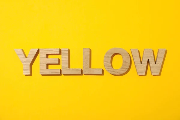 Word jaune disposé en lettres en bois sur fond de couleur — Photo