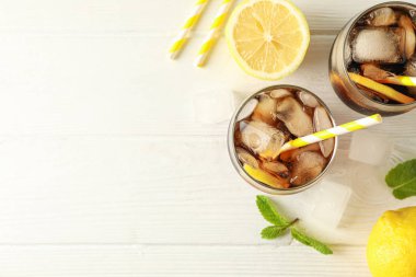 Beyaz ahşap arka planda soğuk kola ve narenciye ile Gözlük,