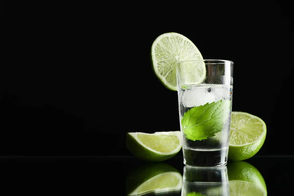 Tequila shot com limão, hortelã e gelo contra fundo preto — Fotografia de Stock